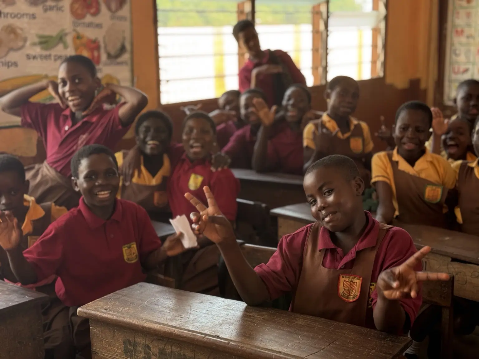 Children smiling and participating together during an Ayola school session.